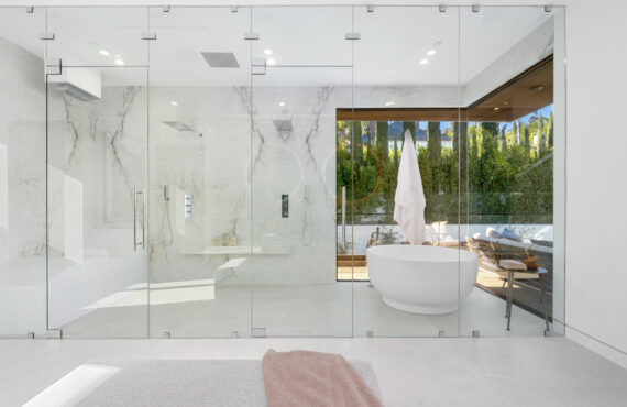 Spacious bathroom with a bathtub behind glass panels